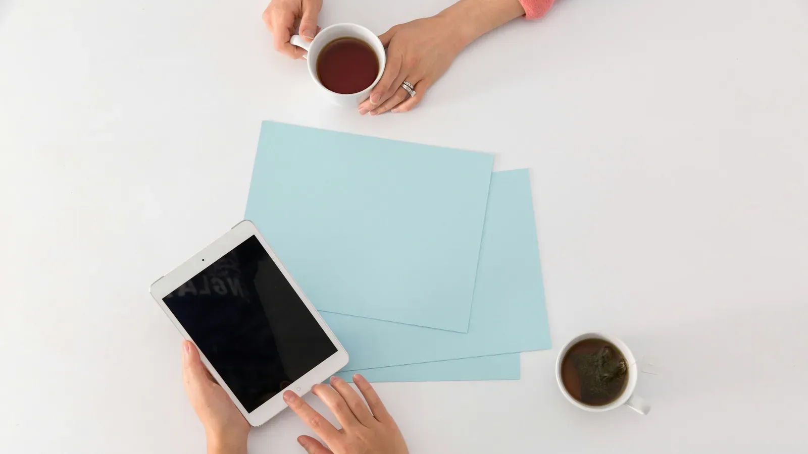 Tablet, Notizkarten und Kaffee auf einem weißen Tisch von oben