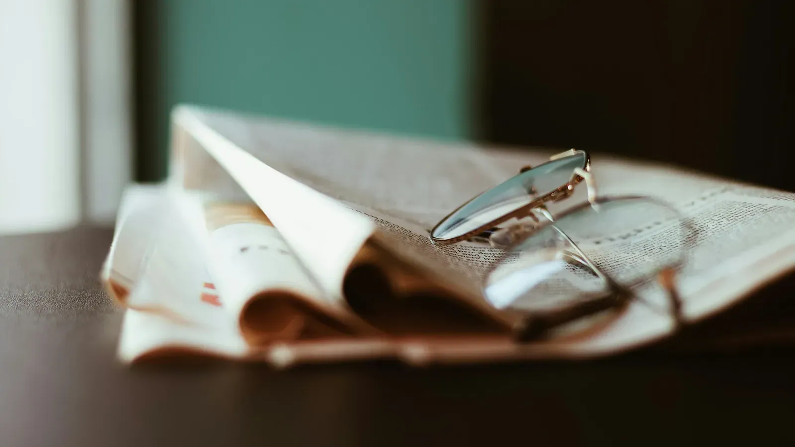 Zusammengefaltete Zeitung mit Lesebrille auf einem Tisch